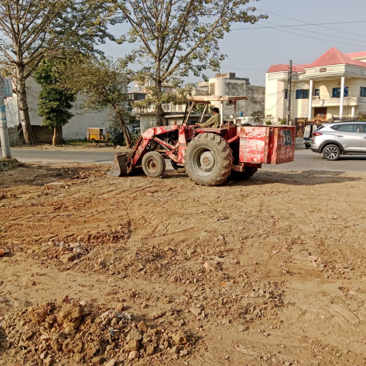 A tractor clearing and levelling the ground beside the road