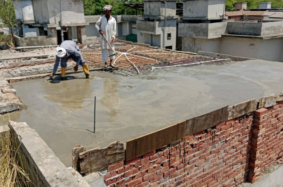 Workers levelling freshly poured concrete over the roof steel