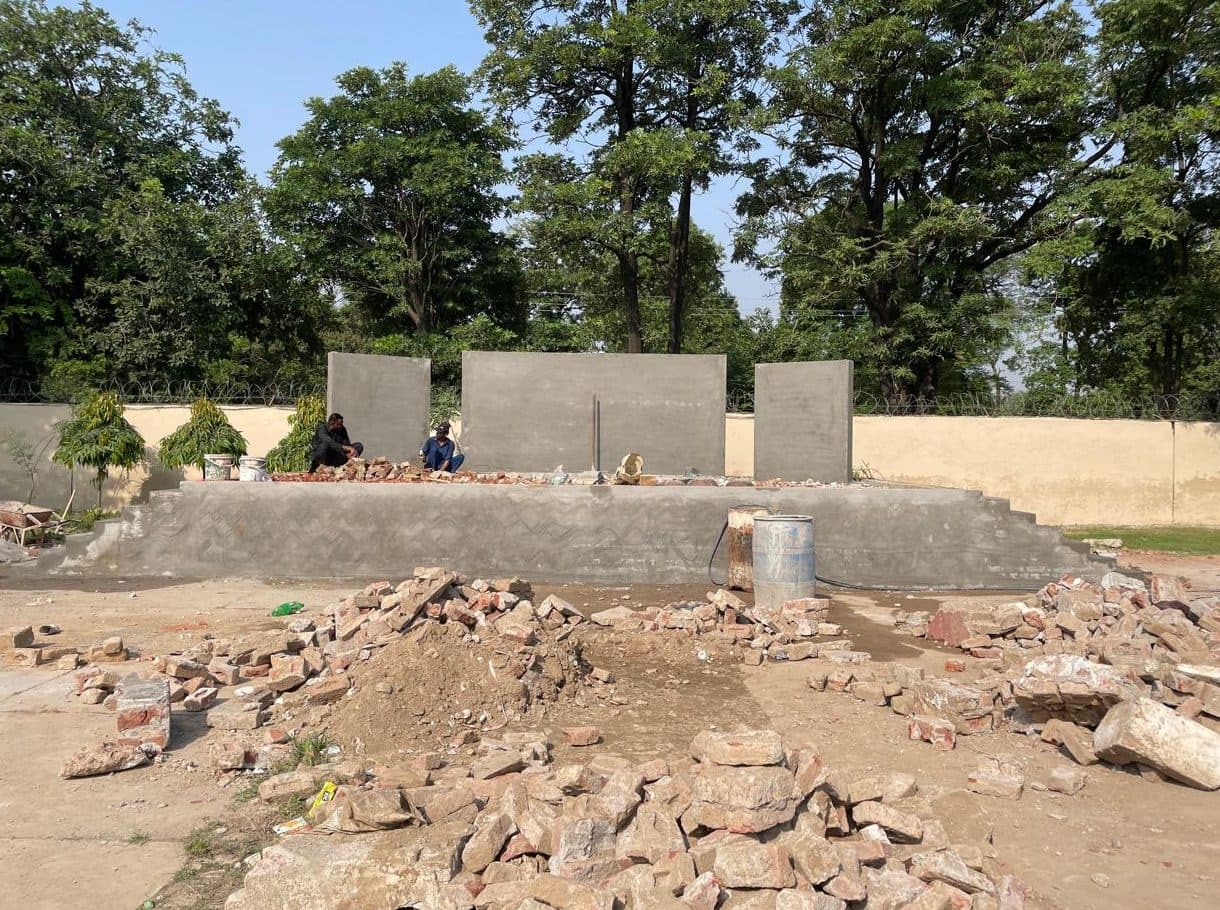 Stage platform with grey plastered walls, rubble and workers in front