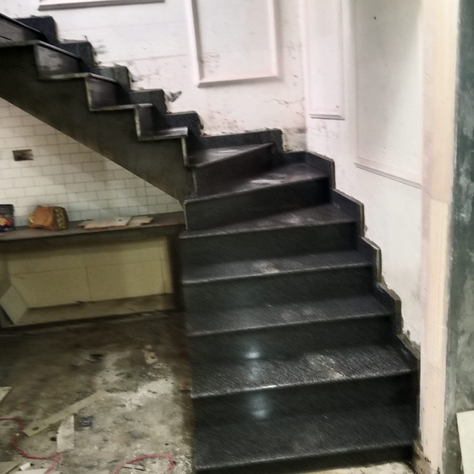 A black granite staircase with new treads and risers, seen from the side
